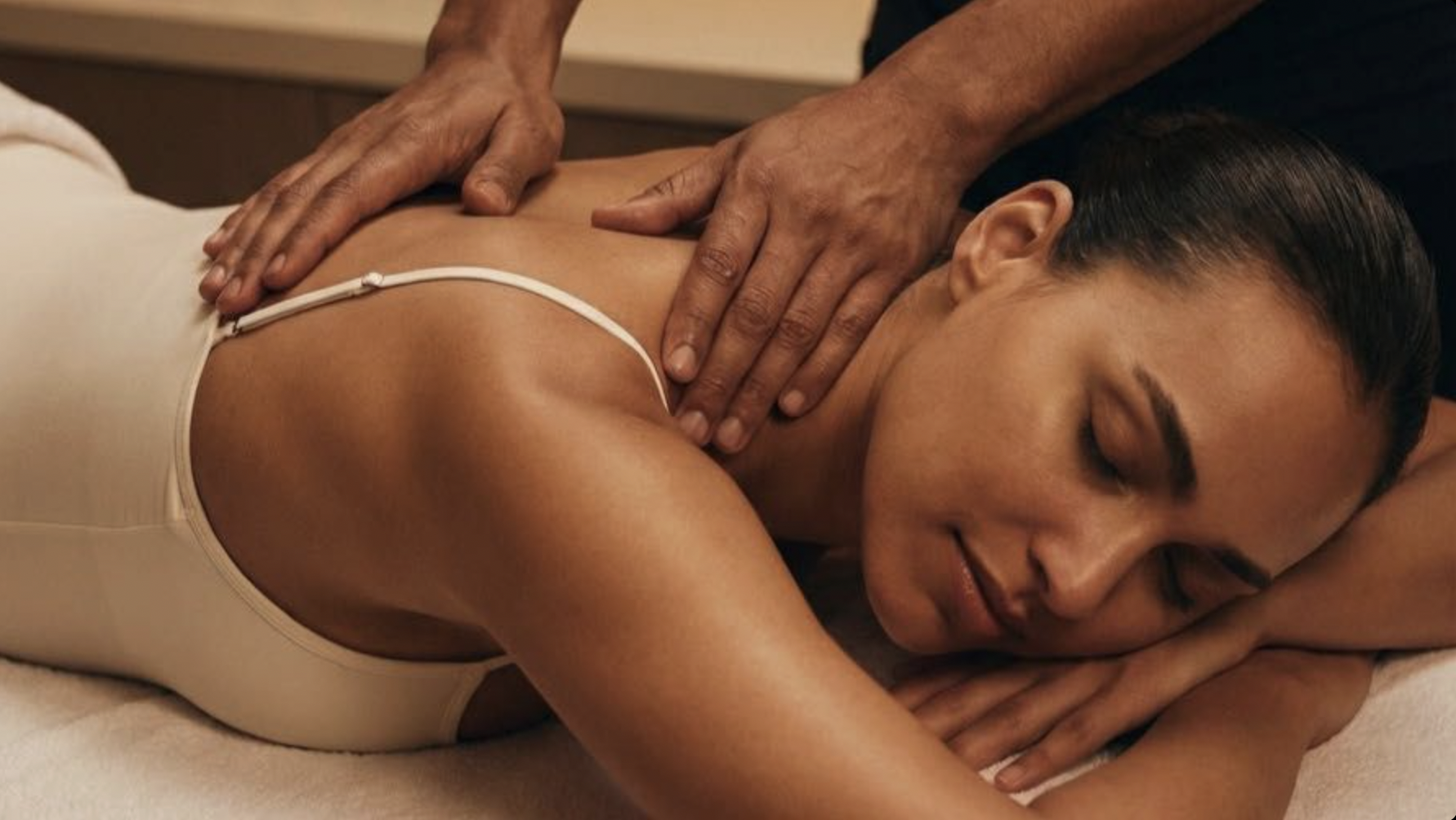Close-up of an in-home back massage with sunlight streaming across the client